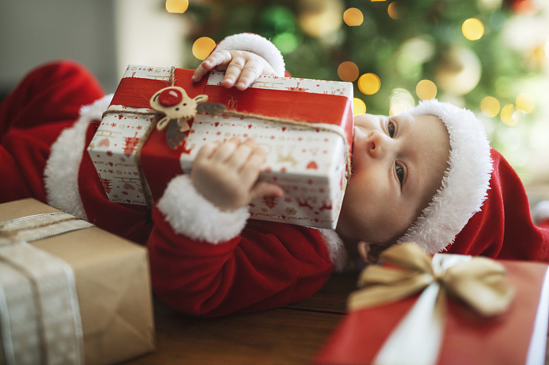 可爱的小男孩打扮成圣诞老人，享受圣诞礼物。图片下载