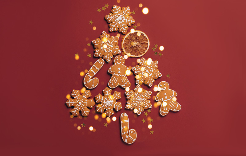 用姜饼饼干做成的圣诞树，红色的节日背景和闪闪发光的彩纸平铺图片下载