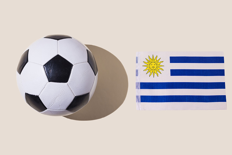 复古足球旁边是乌拉圭的国旗，白色，蓝色条纹和一个太阳，在柔和的背景。足球，足球世界杯，体育，比赛和世界冠军的概念图片下载