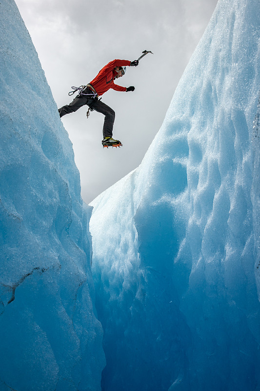 一名登山者跳过冰川大裂缝图片下载