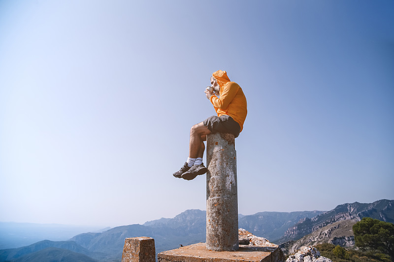 一个人坐在岩石上，边喝咖啡边看山谷图片下载