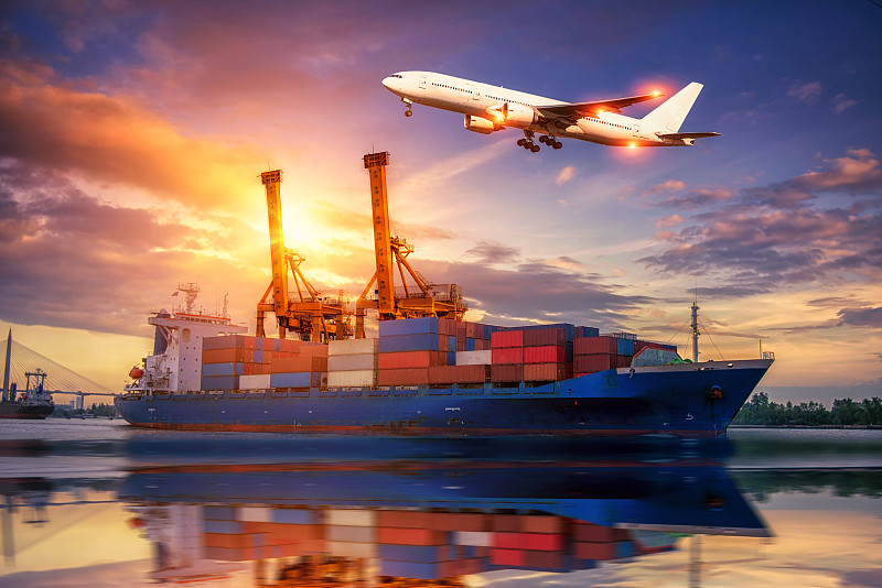 物流与运输的集装箱货轮和货机与工作起重机桥在日出船厂，物流进出口和运输行业背景图片素材