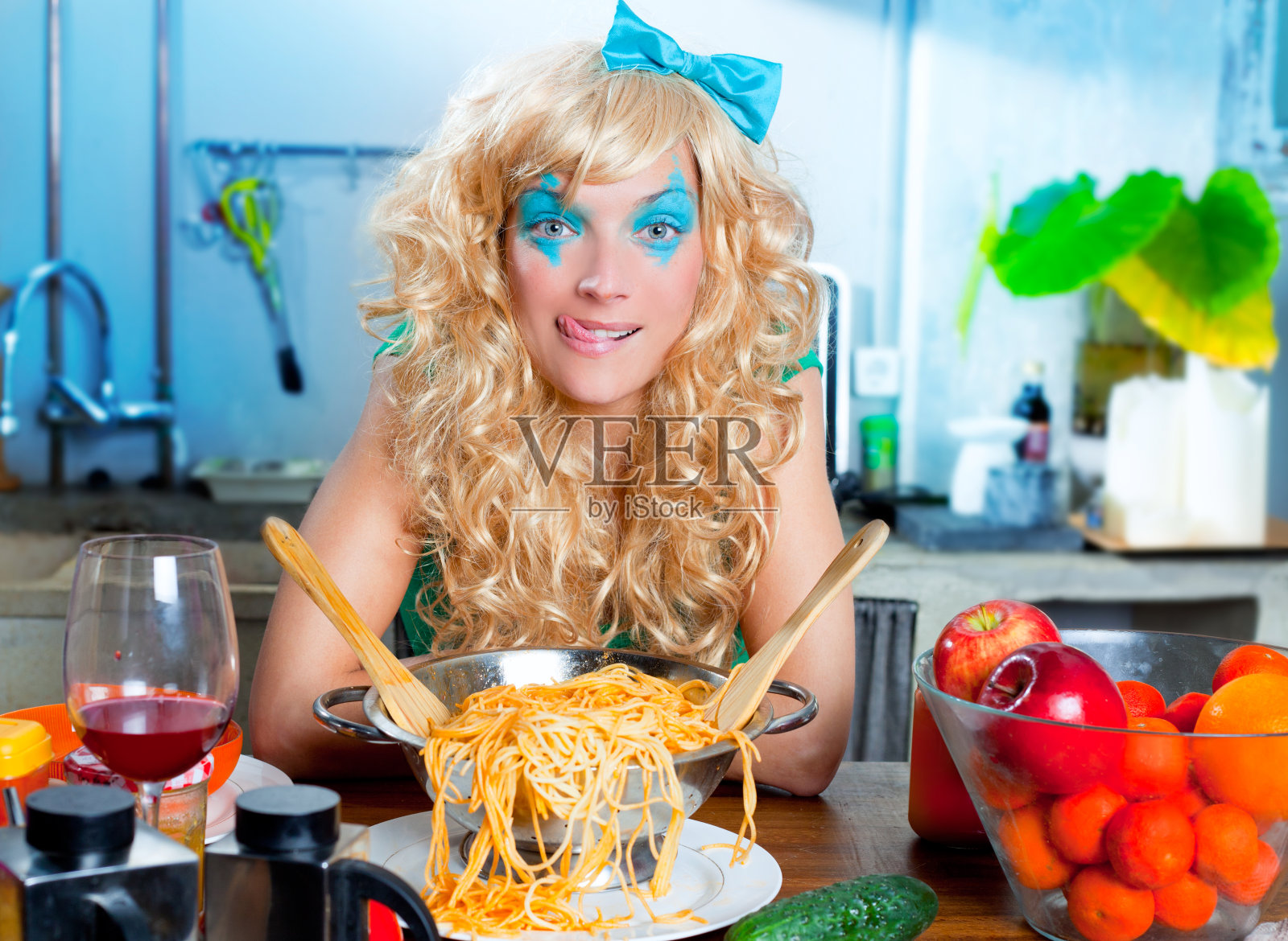 金发美女在厨房里吃着意大利面，很饿照片摄影图片