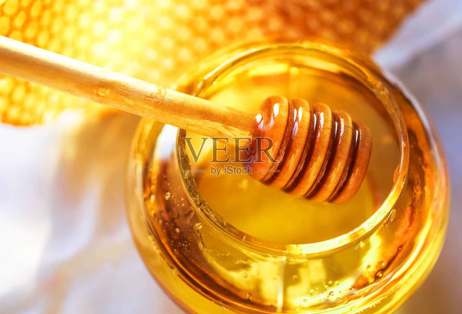 蜂蜜在一个玻璃罐子旁边的蜂巢照片摄影图片
