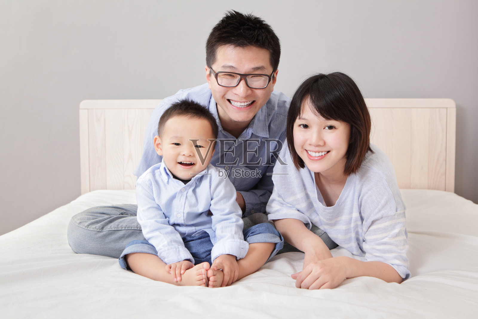幸福的一家人坐在白色的床上照片摄影图片