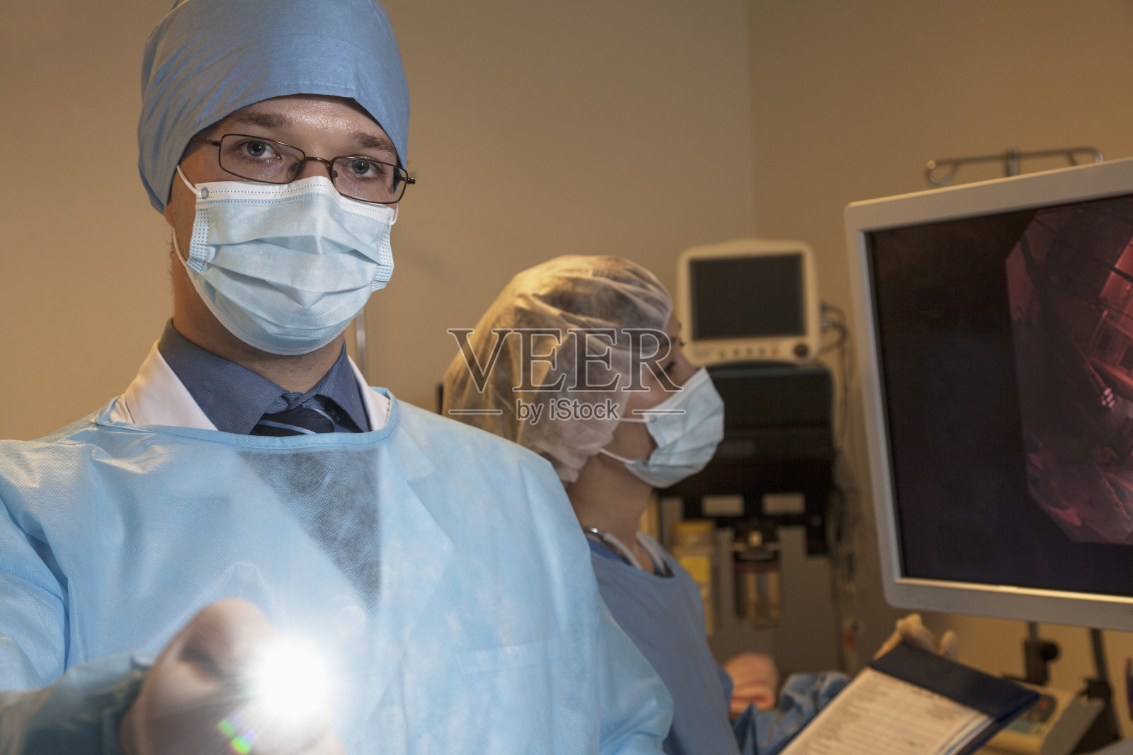 外科医生拿着医疗器械对着摄像机，灯光闪烁照片摄影图片