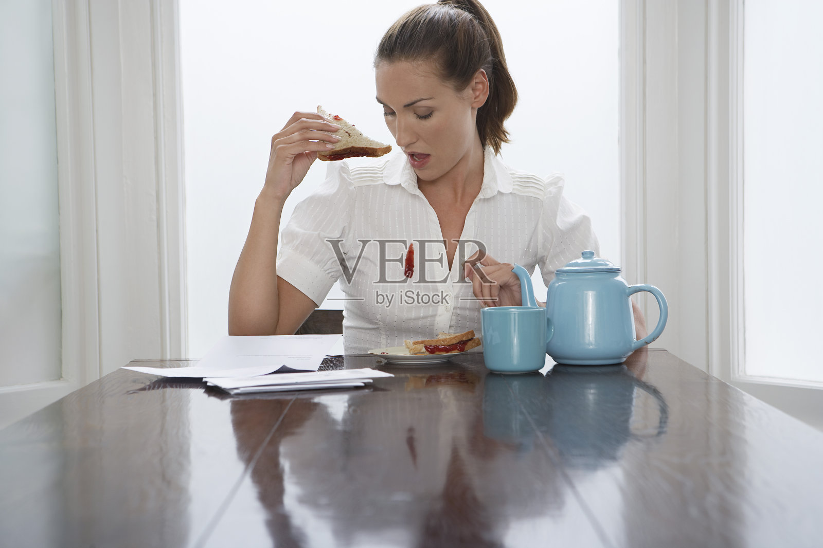 一个女人在吃早饭时把果酱掉在衬衫上照片摄影图片