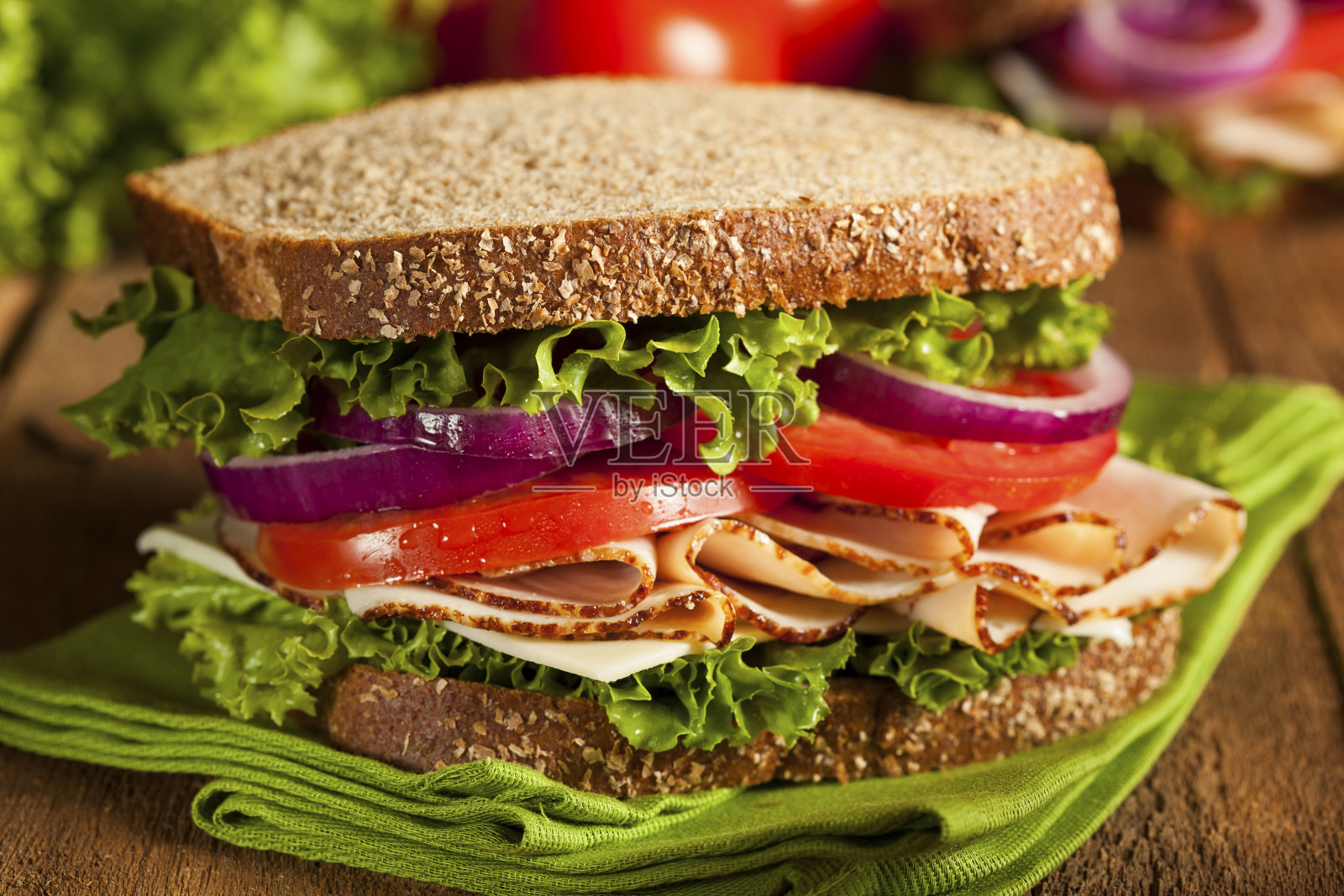 一种用西红柿、洋葱和莴苣夹在小麦面包上的三明治照片摄影图片