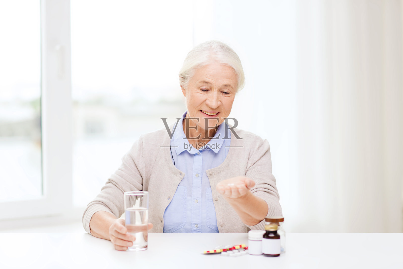 快乐的老年妇女在家里水和药照片摄影图片