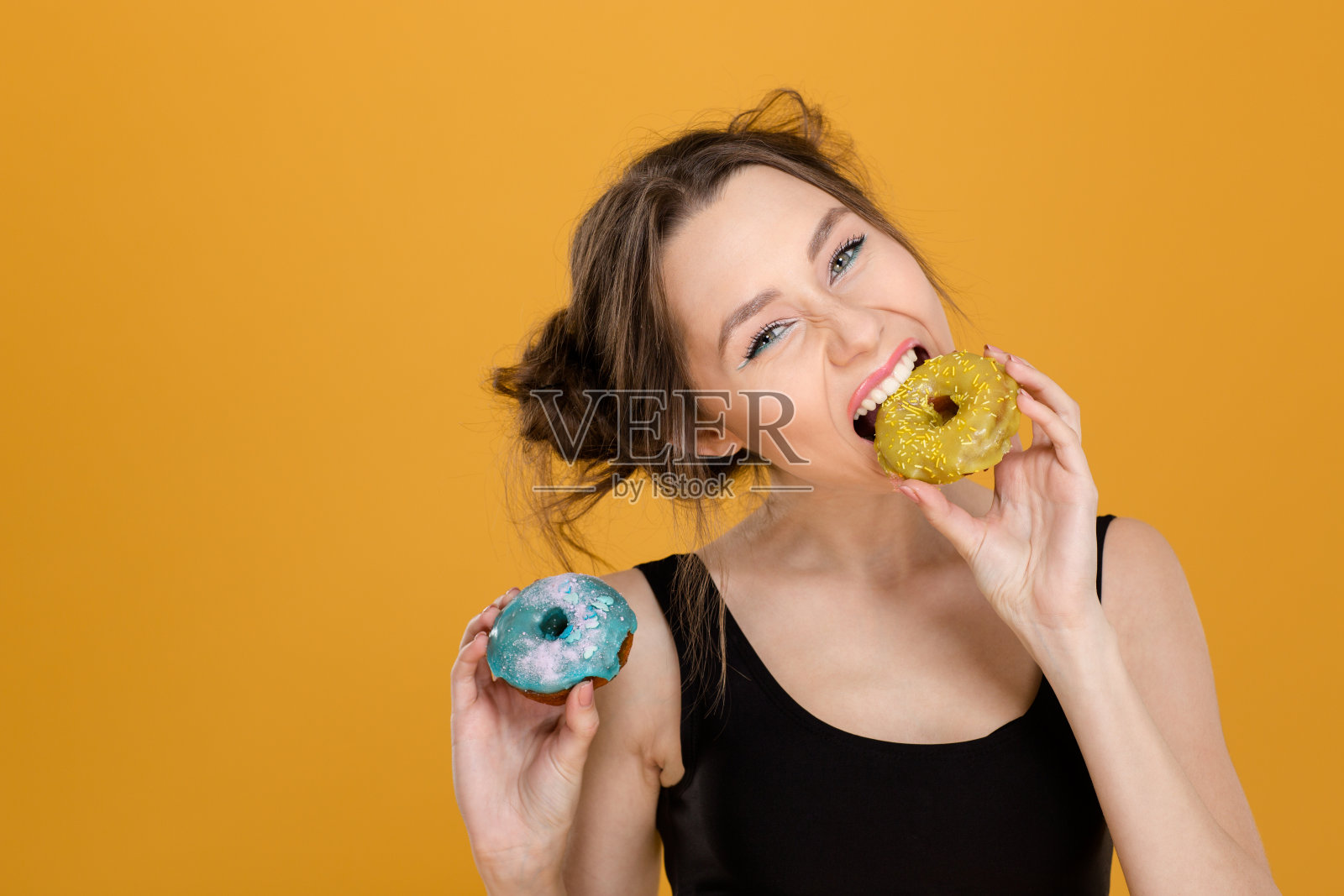 非常积极的年轻女子在吃五颜六色的甜甜圈照片摄影图片