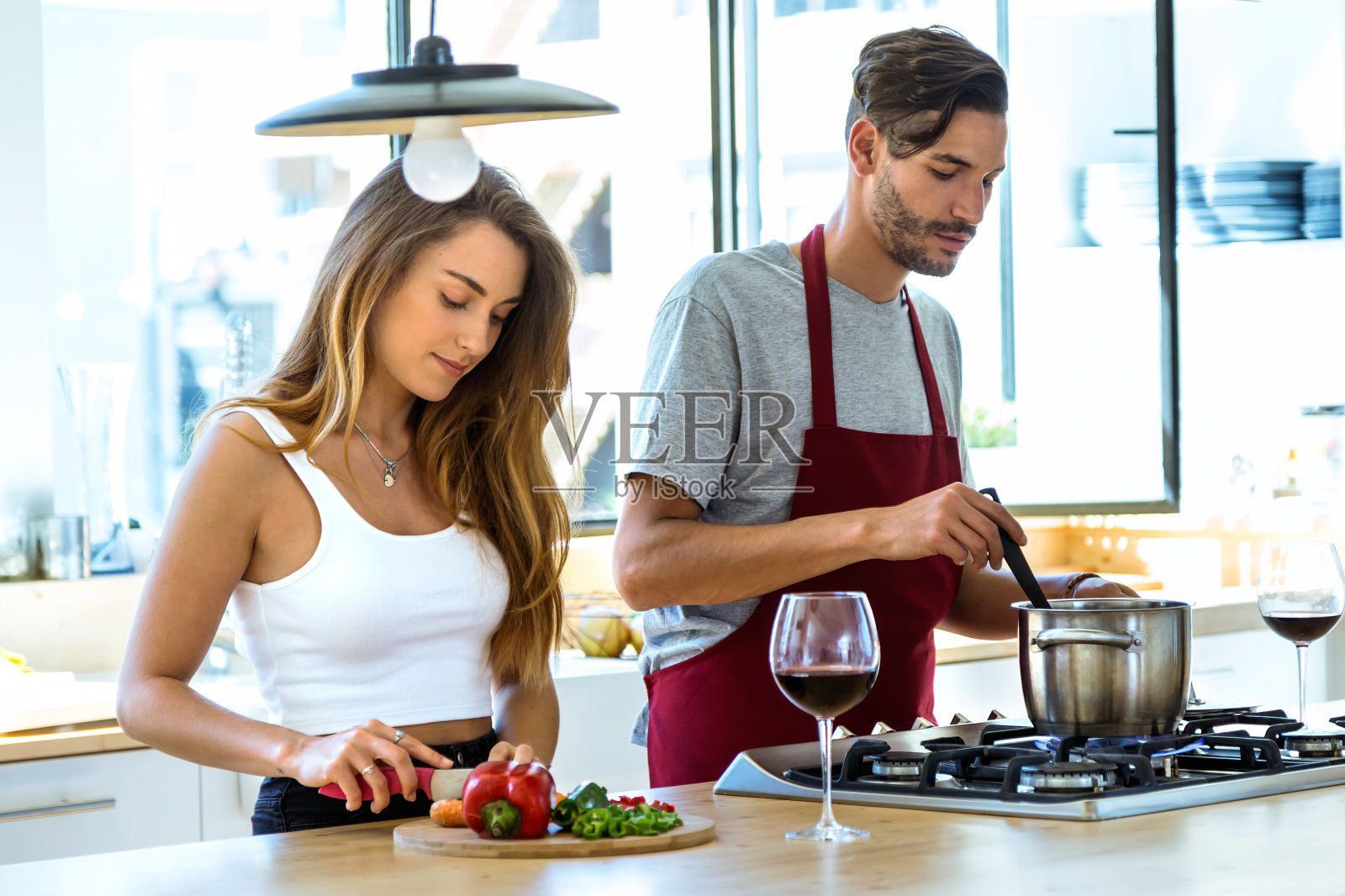 幸福的年轻夫妇在家里的厨房里一起做饭。照片摄影图片