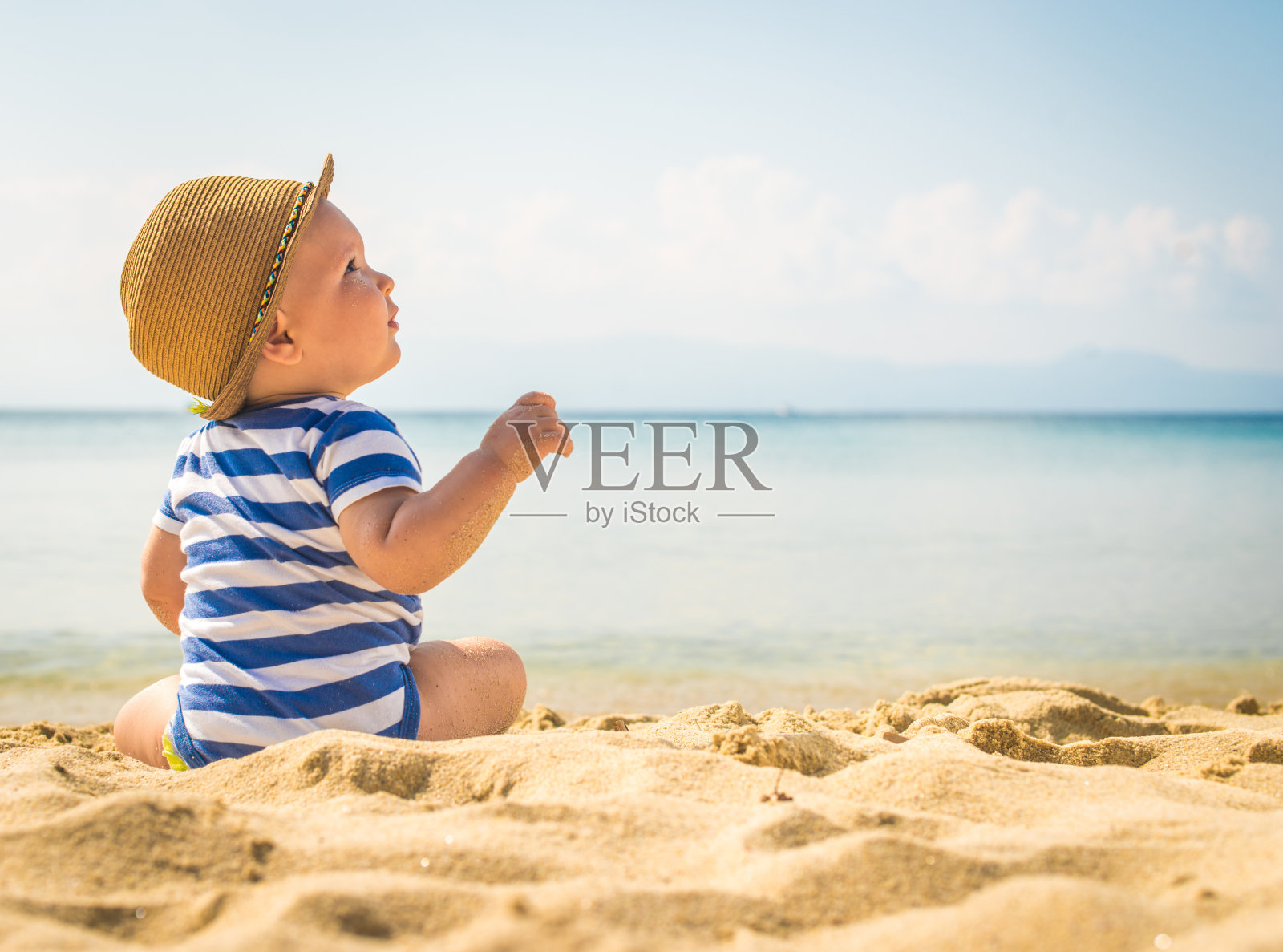 小男孩坐在沙滩上照片摄影图片
