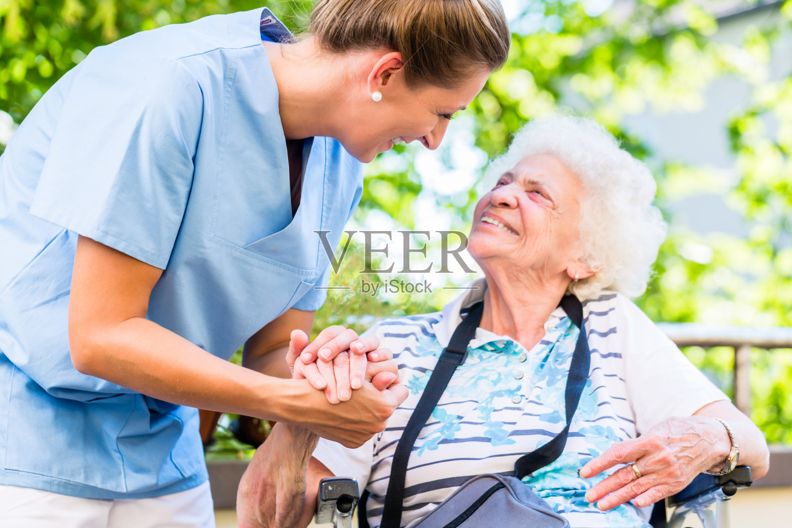 在养老院里，护士牵着老年妇女的手照片摄影图片