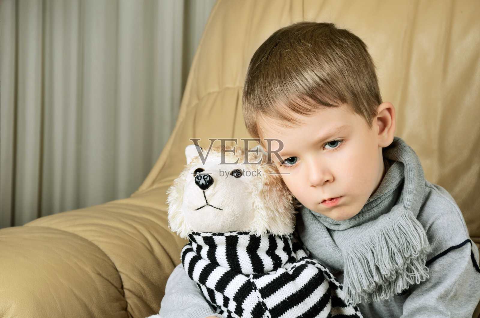 悲伤的小男孩抱着玩具狗照片摄影图片