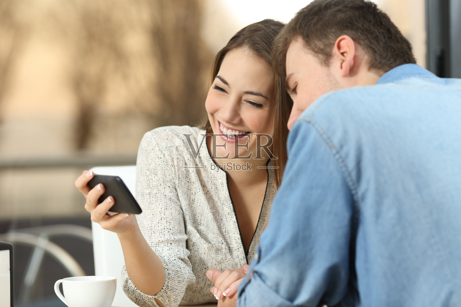 一对情侣在酒吧里用智能手机分享媒体照片摄影图片