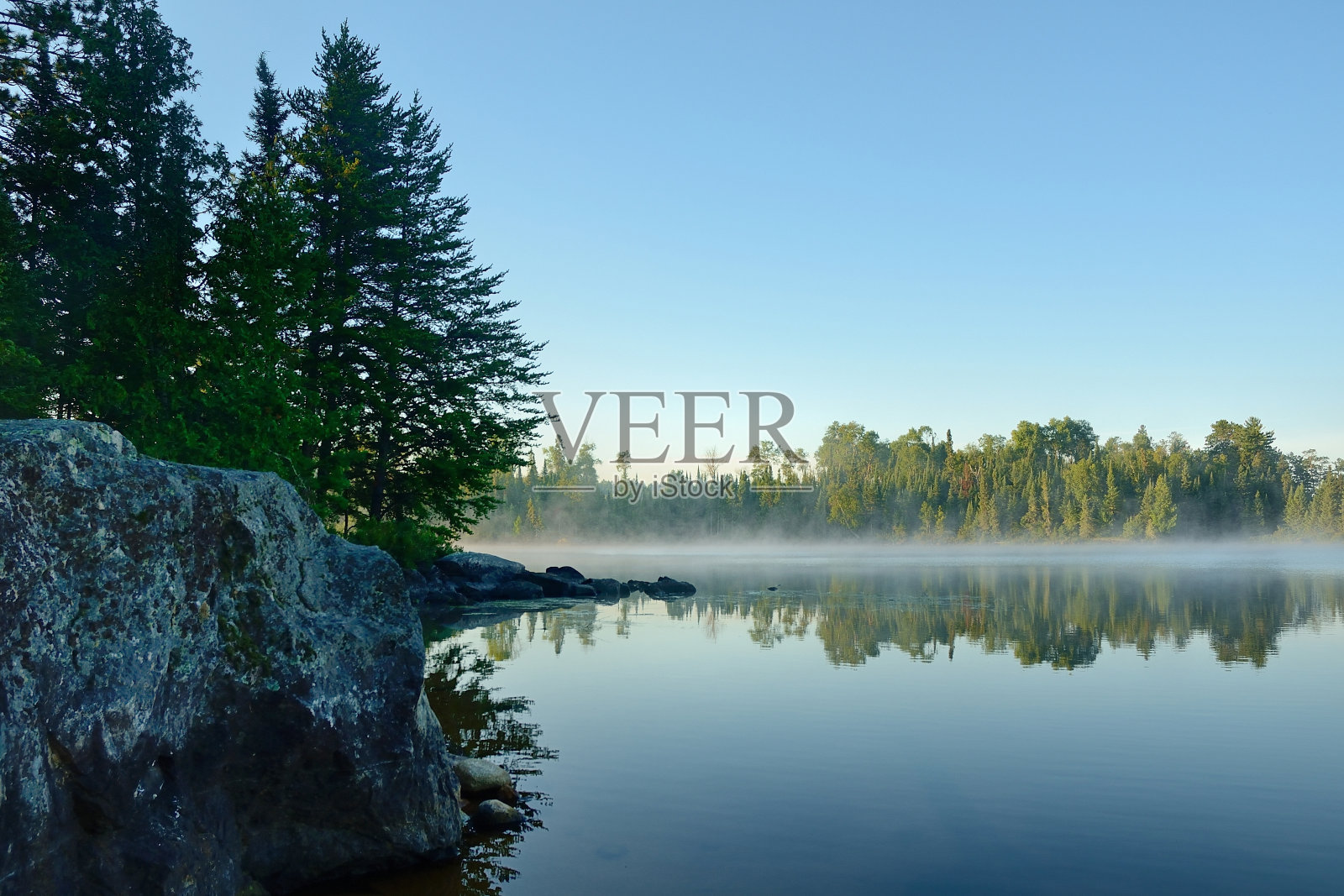 早晨的倒影在一个雾蒙蒙的荒野湖照片摄影图片