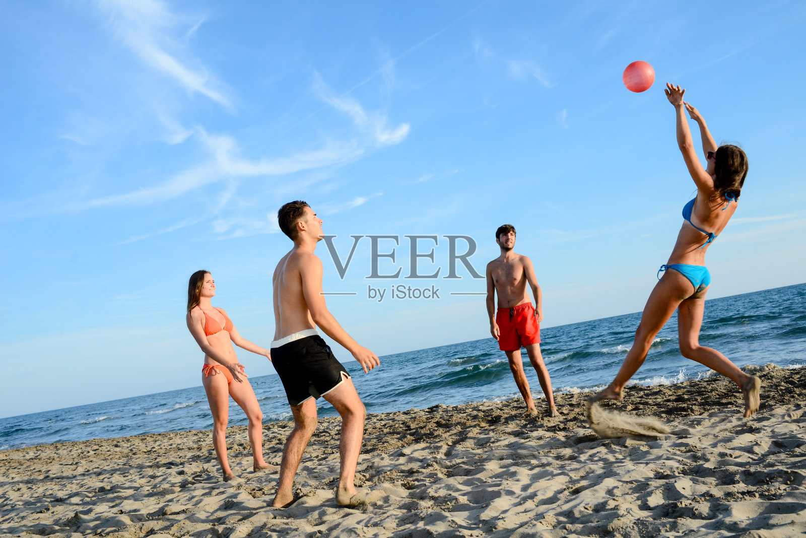 四个年轻人在海边玩沙滩排球度过暑假照片摄影图片