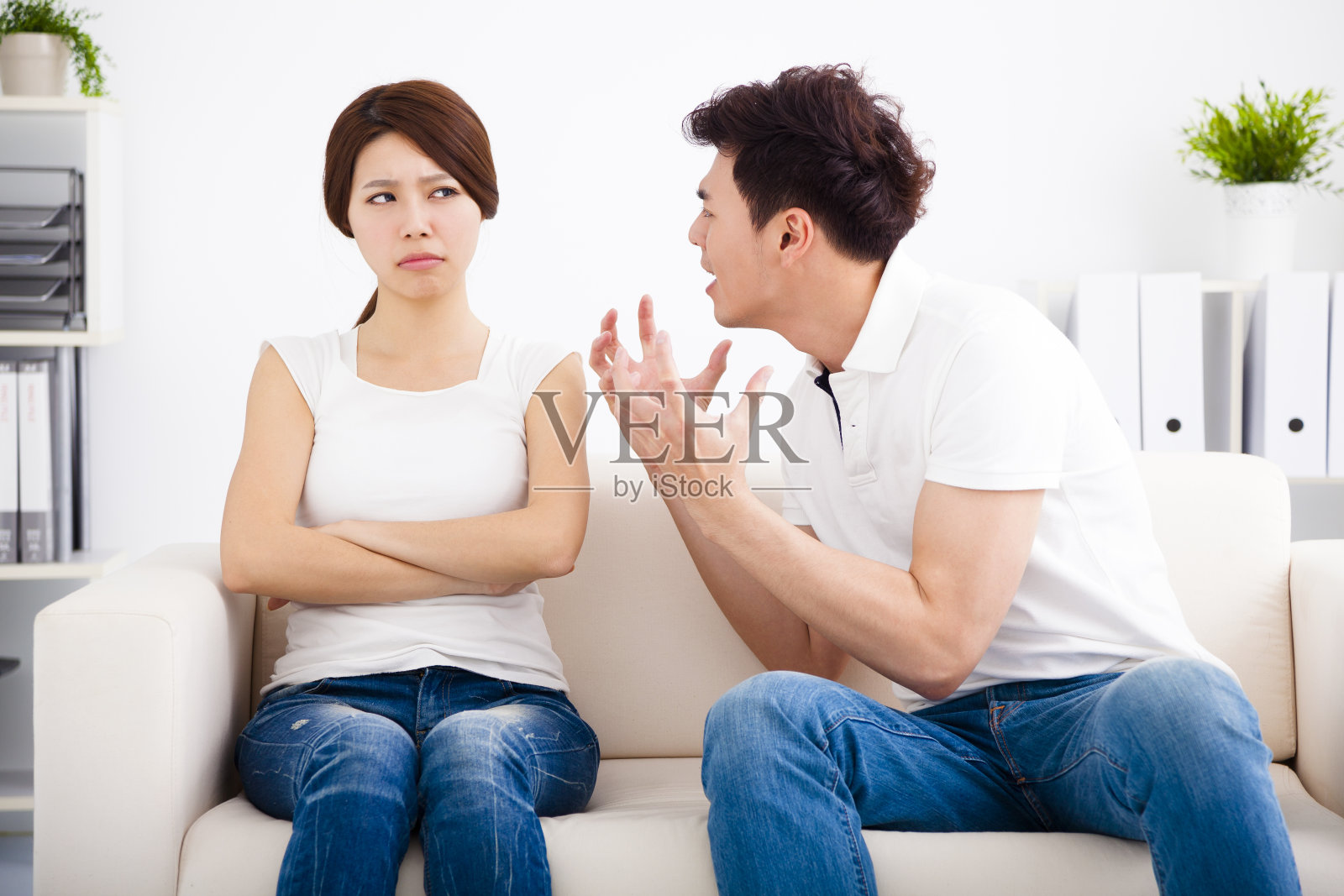 一对愤怒的年轻夫妇坐在沙发上照片摄影图片
