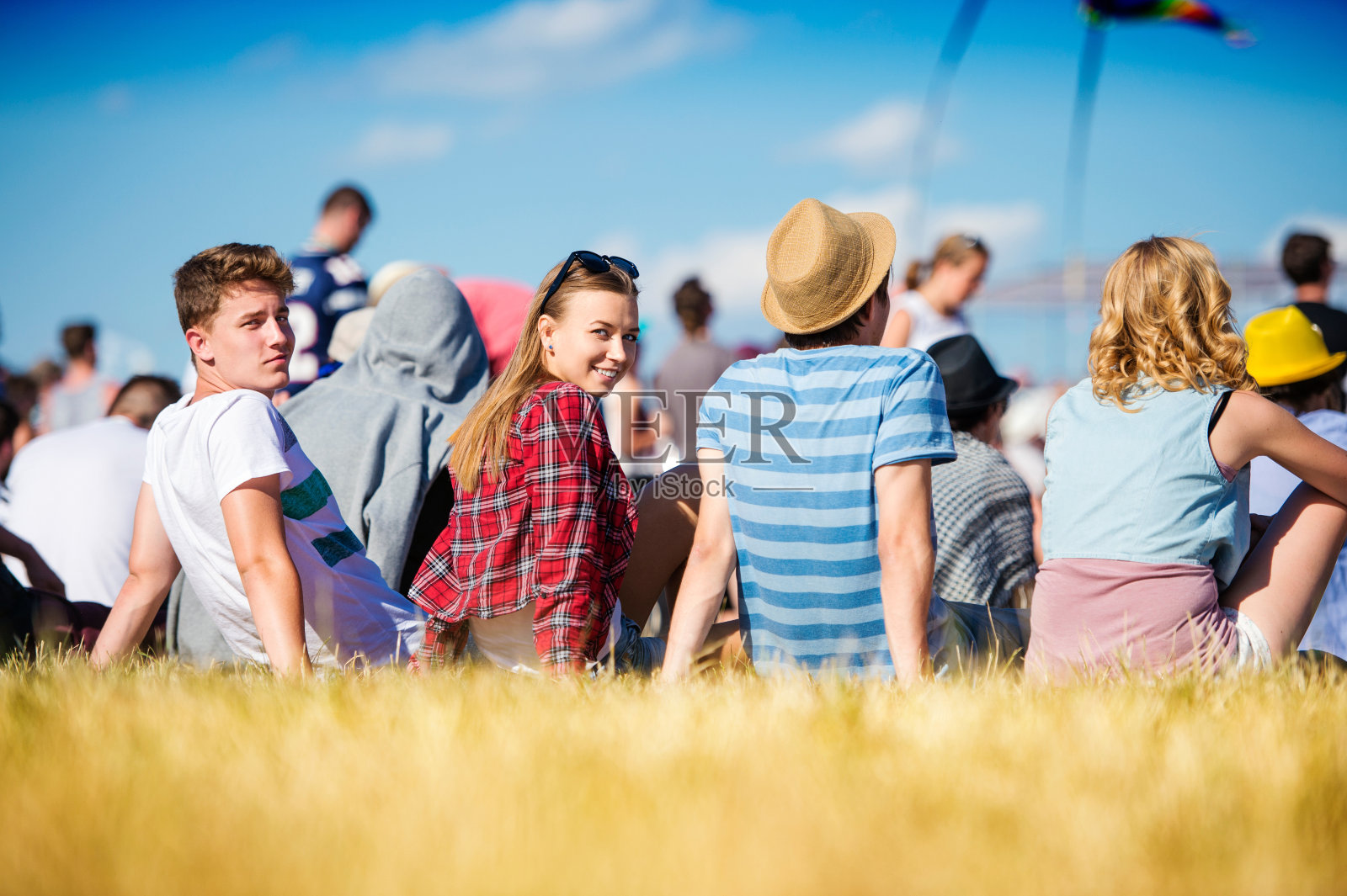 青少年在夏季音乐节上，坐在草地上照片摄影图片