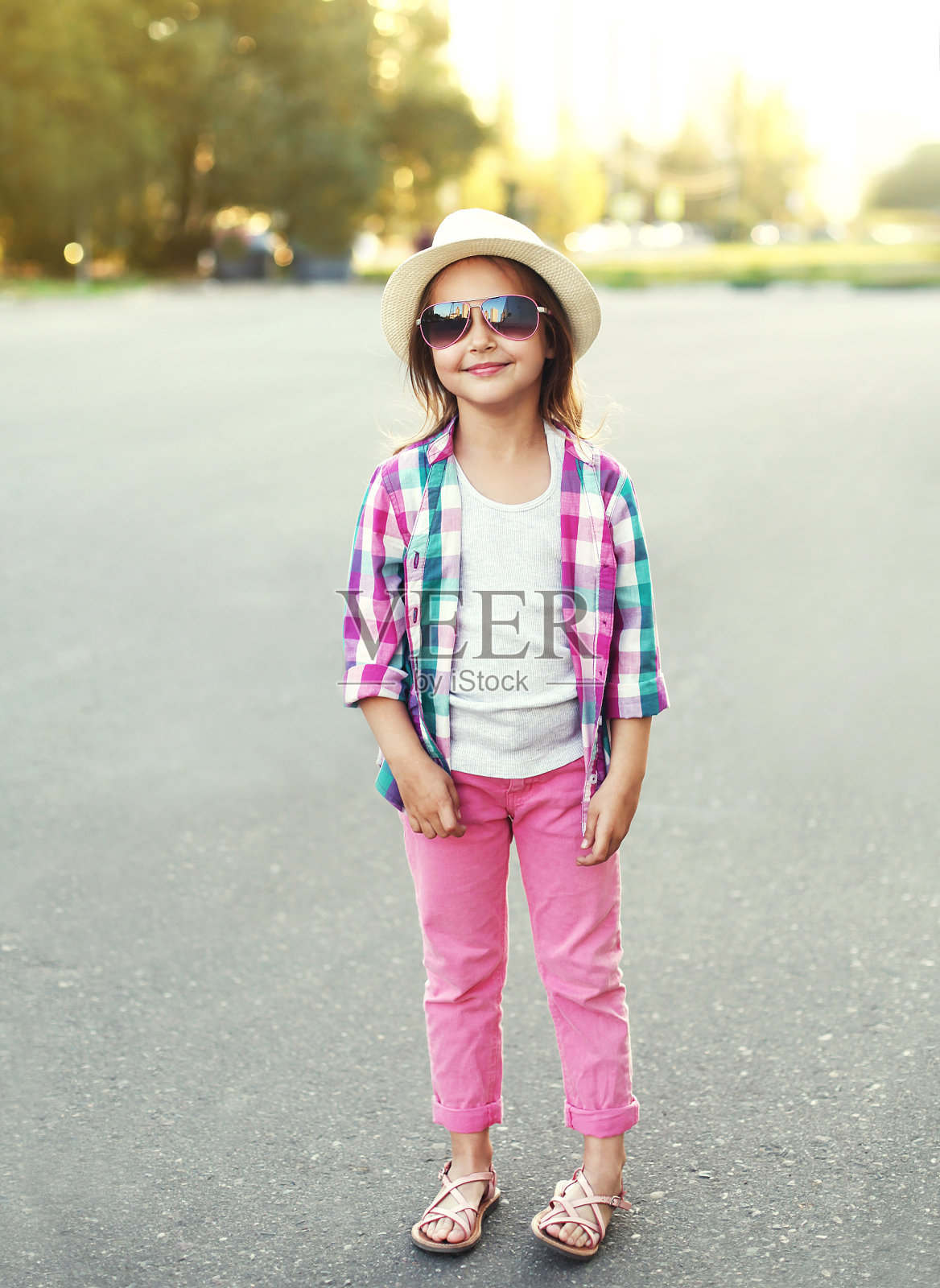 时尚微笑的小女孩孩子穿着衬衫，帽子和太阳镜照片摄影图片
