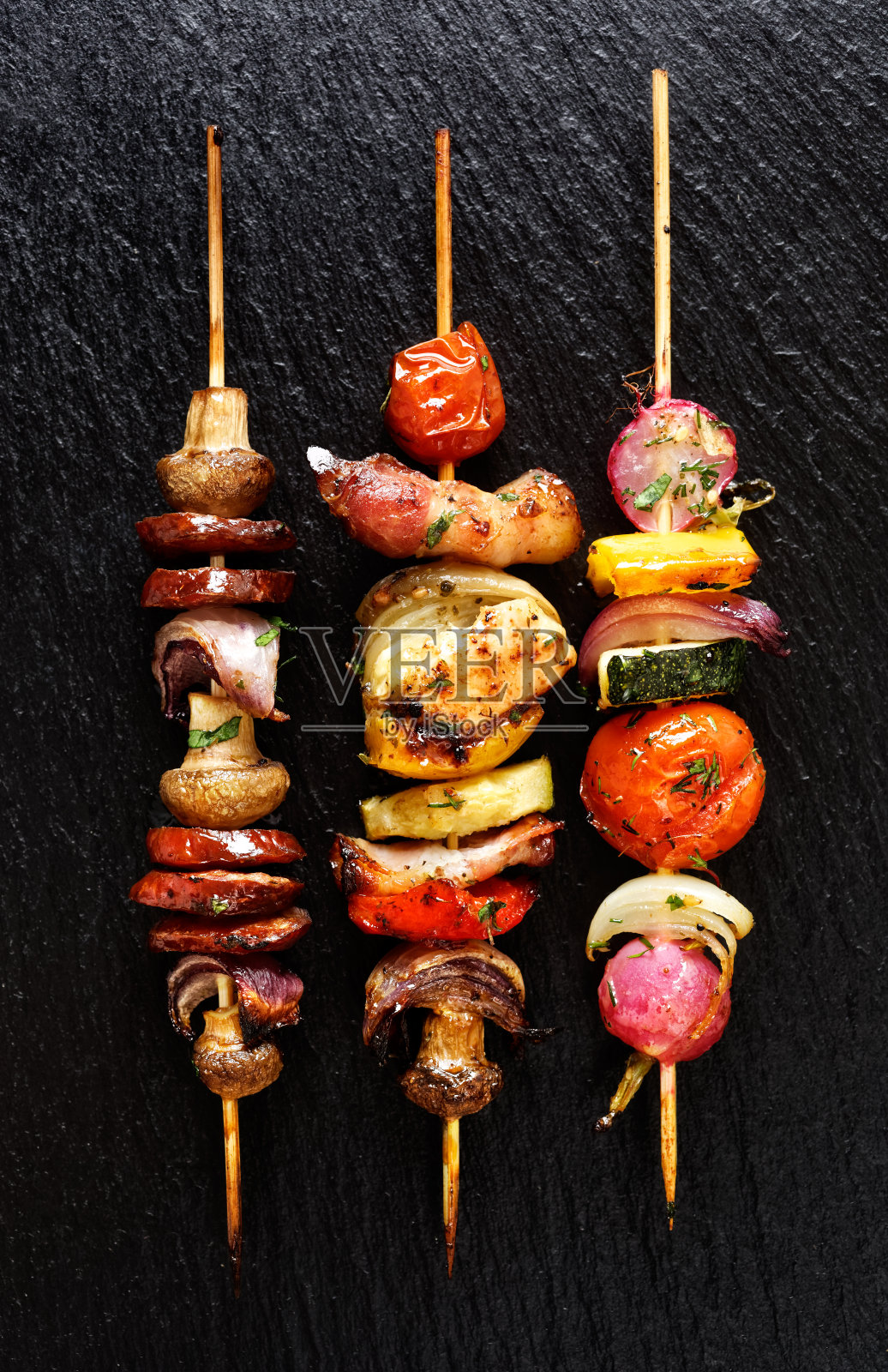 黑色石头背景上的烤蔬菜和肉串照片摄影图片