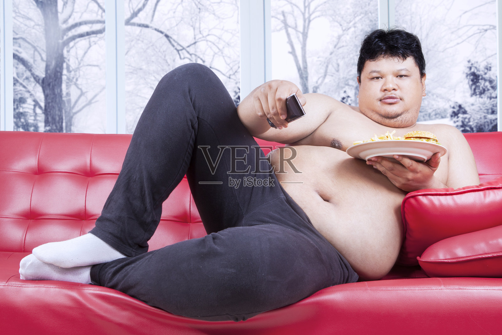胖子一边吃快餐一边看电视照片摄影图片