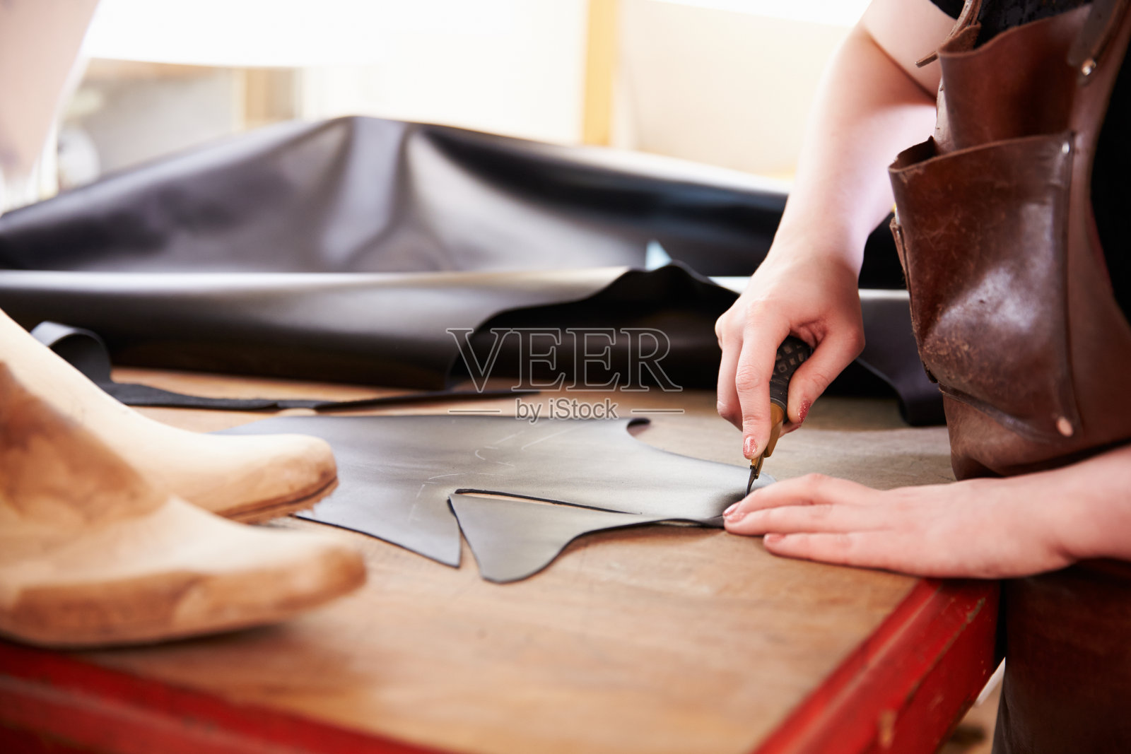 一个鞋匠在车间里裁剪皮革，特写照片摄影图片