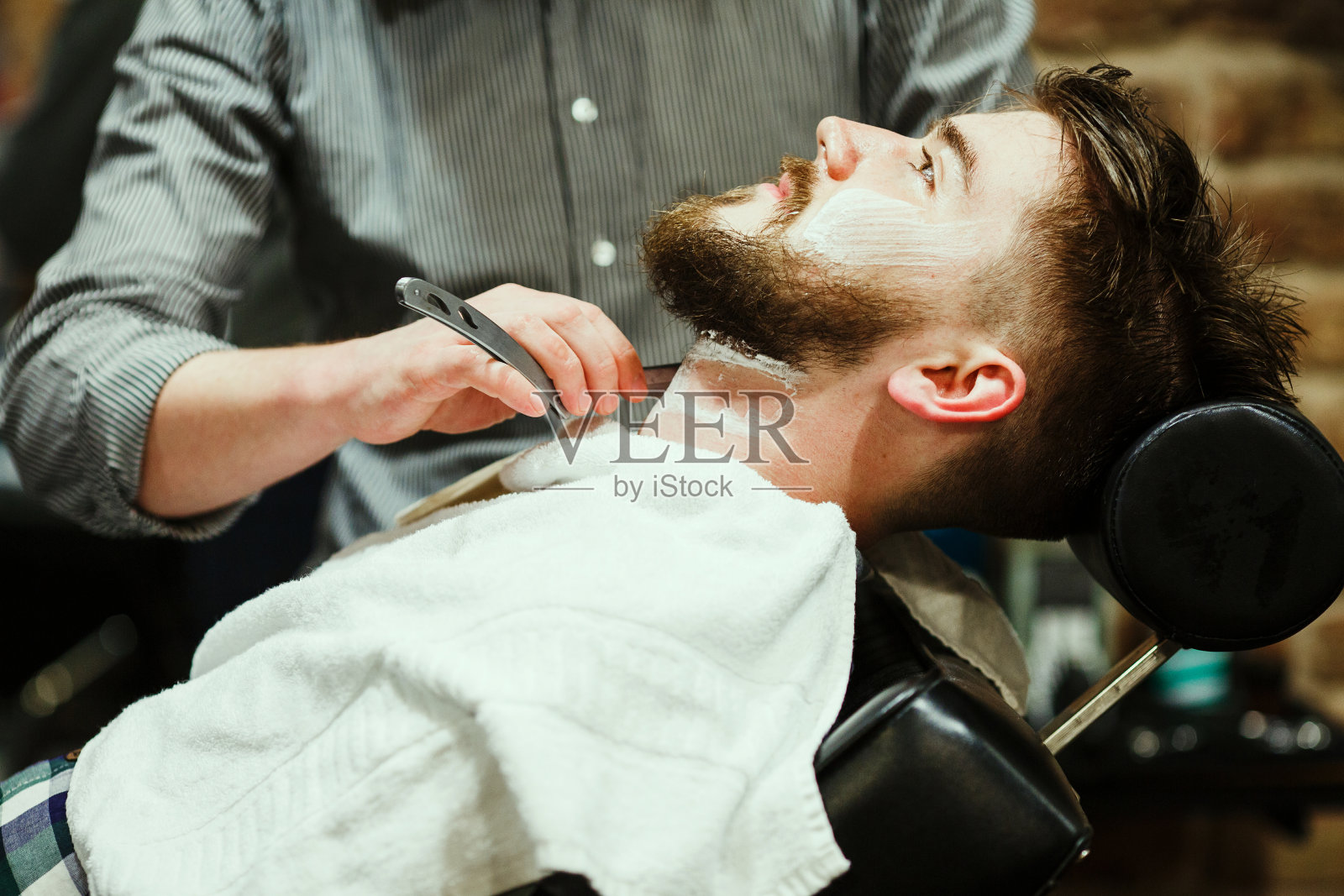 理发师在给一个留胡子的男人刮胡子照片摄影图片