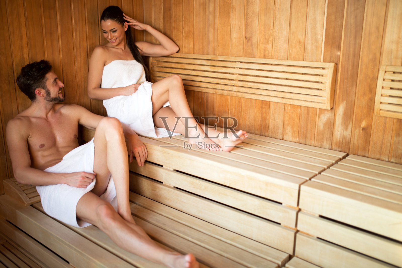 一对美丽的夫妇在桑拿浴室里用毛巾盖着照片摄影图片