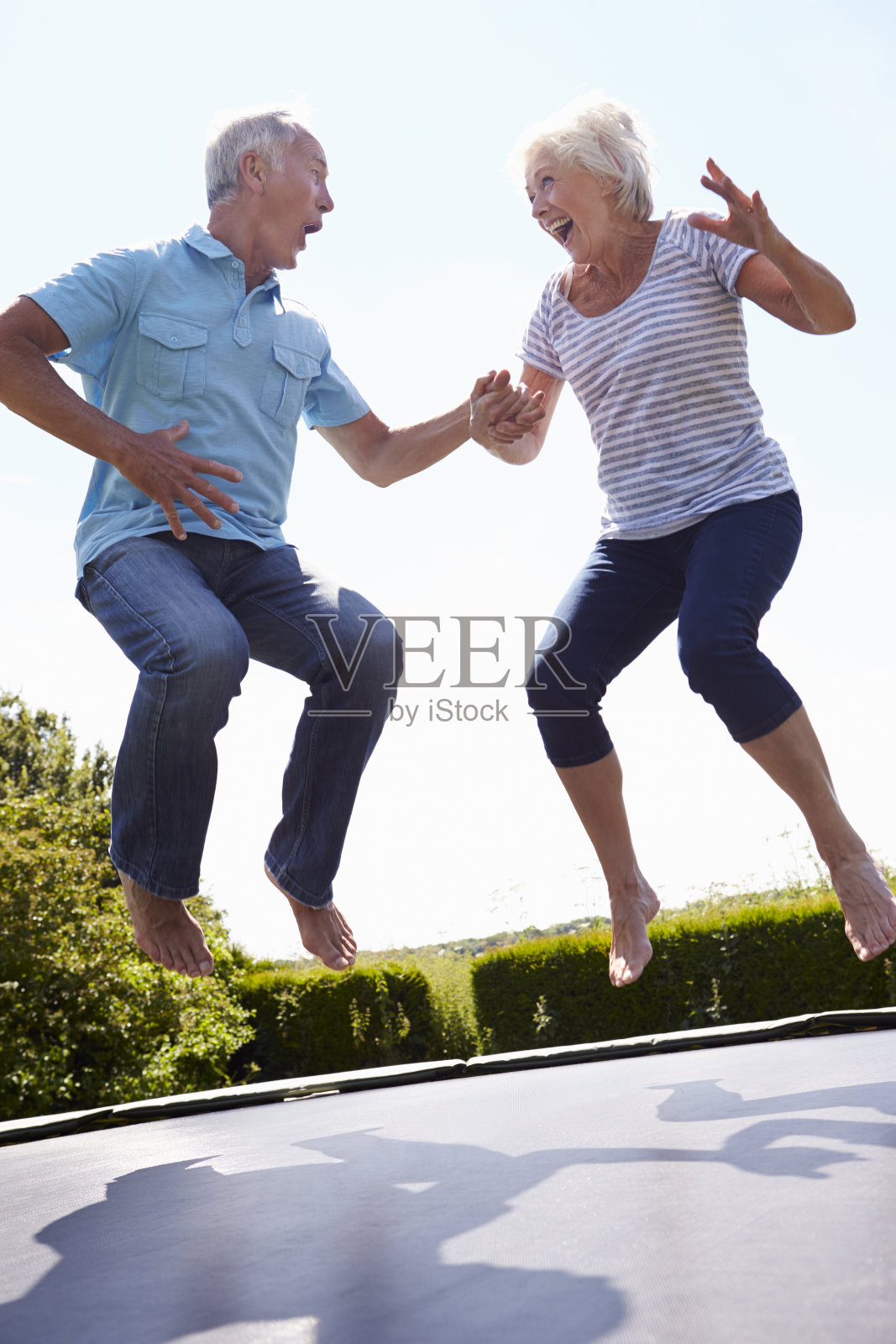 一对老年夫妇在花园里蹦床上蹦蹦跳跳照片摄影图片