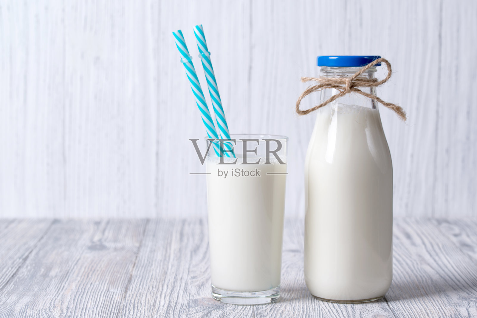 瓶子和杯子的牛奶与吸管，木制的背景照片摄影图片