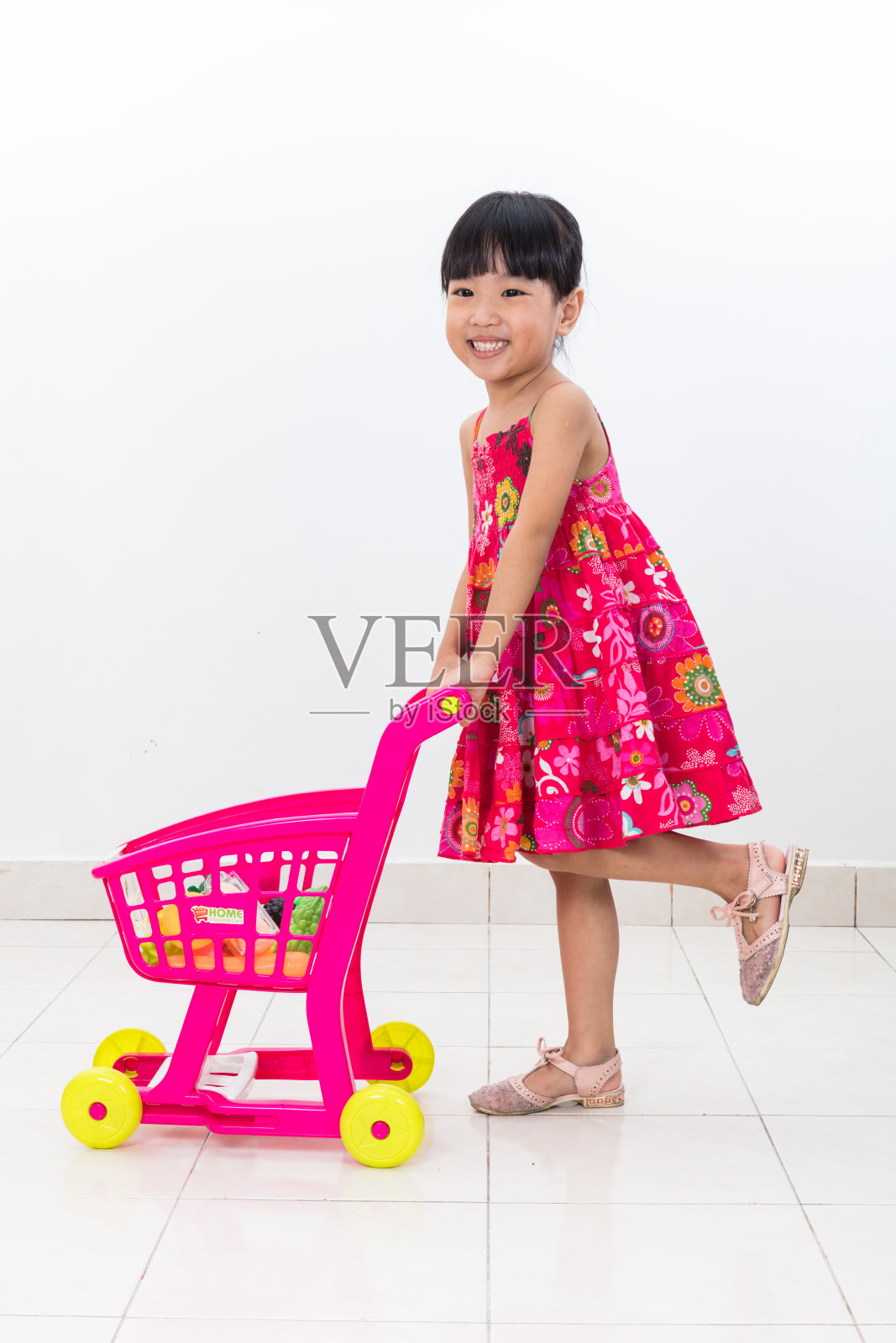 快乐的亚洲华人小女孩推着玩具手推车照片摄影图片
