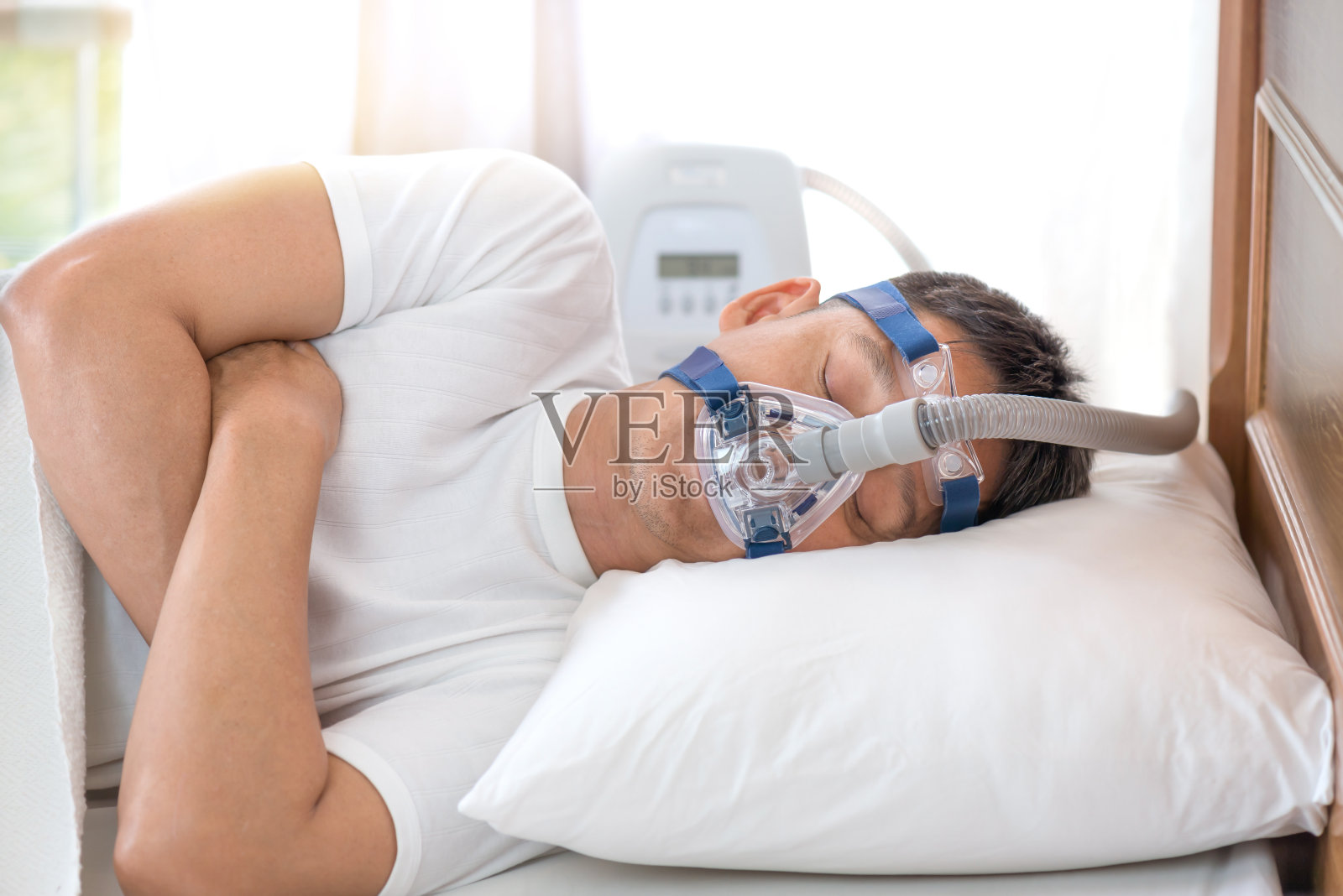 男人戴着呼吸面罩睡在床上，还有睡眠呼吸暂停治疗照片摄影图片