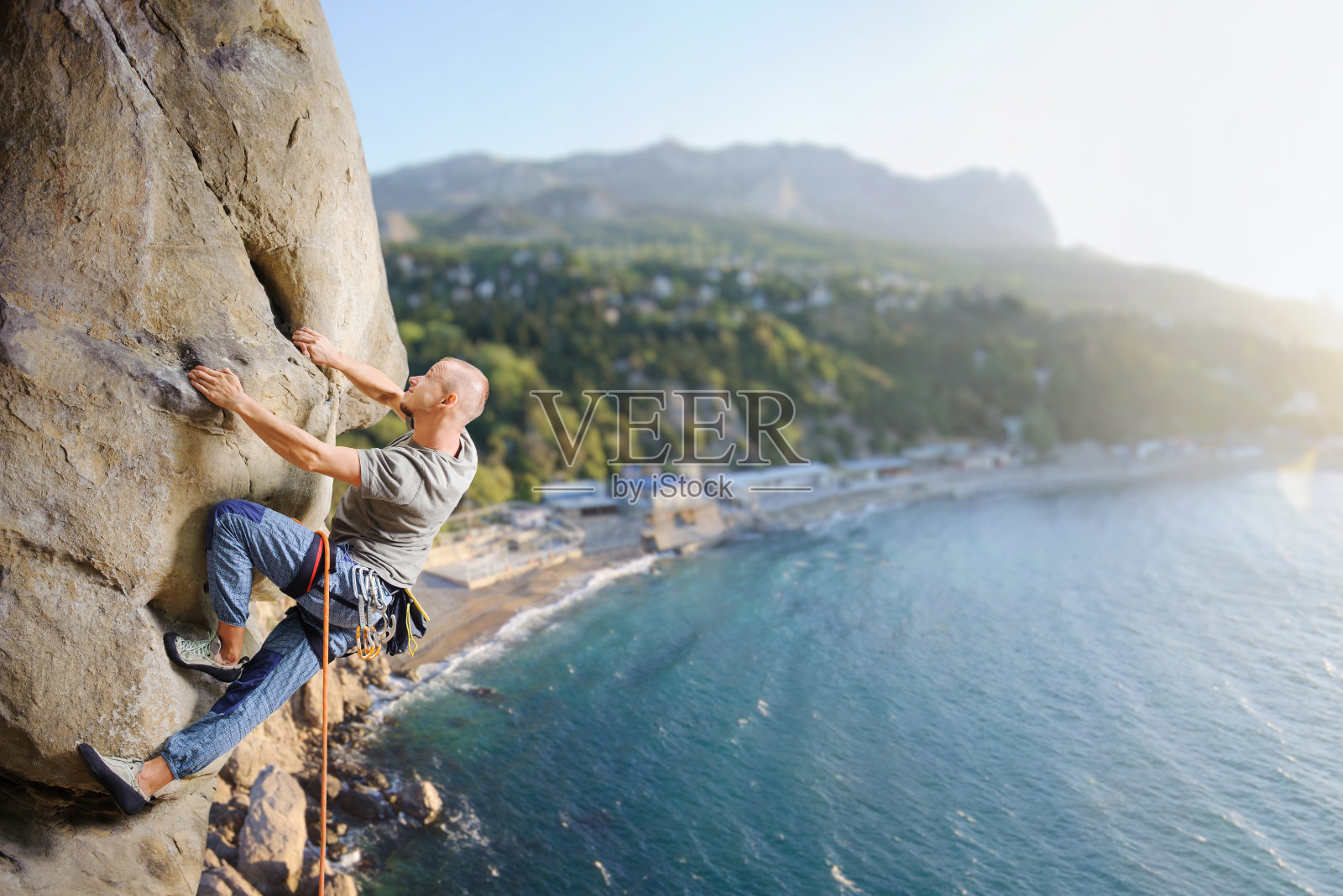 男性攀登者用绳子在大自然中攀爬巨石照片摄影图片