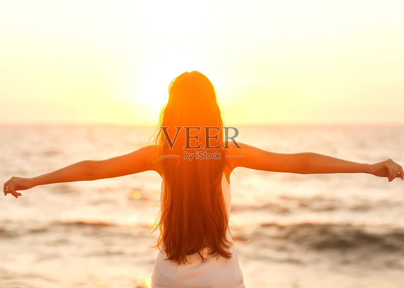 自由的女人享受自由，感觉快乐的海滩日落。照片摄影图片