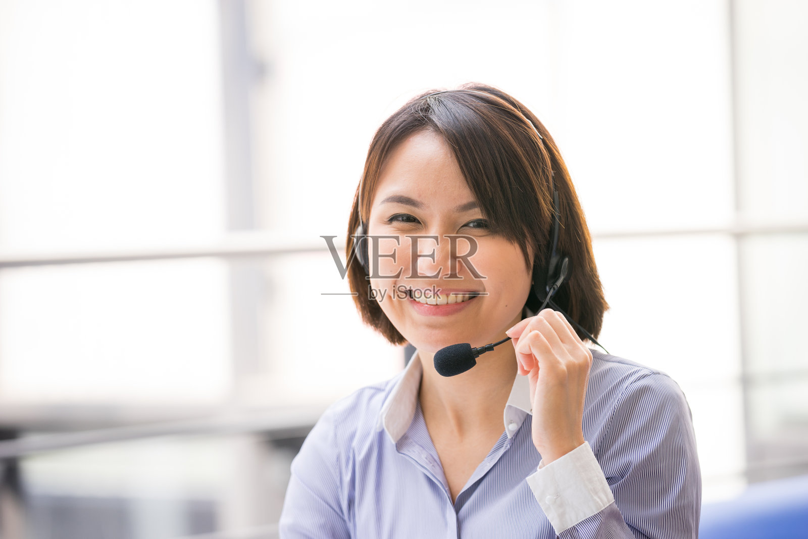 在办公室里用耳机说话的亚洲商务女性照片摄影图片