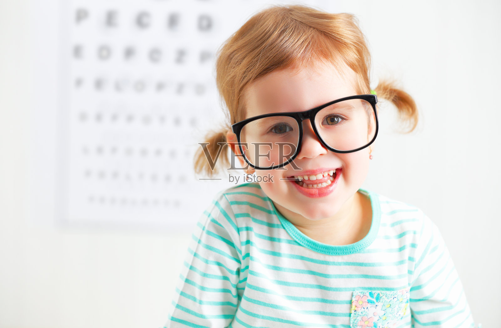 视力测试的概念。戴眼镜的小女孩照片摄影图片