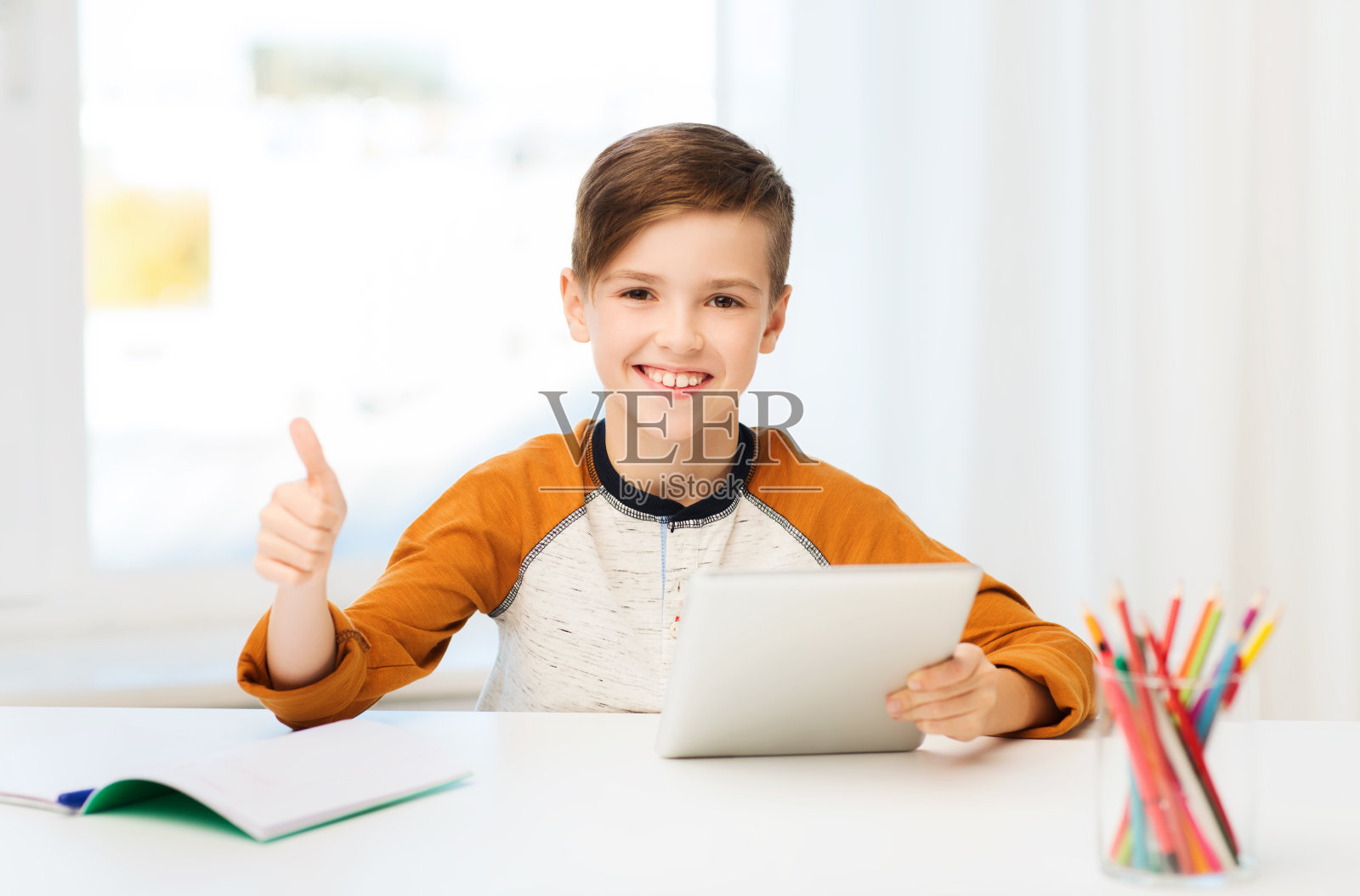 快乐的男孩在家里用平板电脑向大家竖起大拇指照片摄影图片