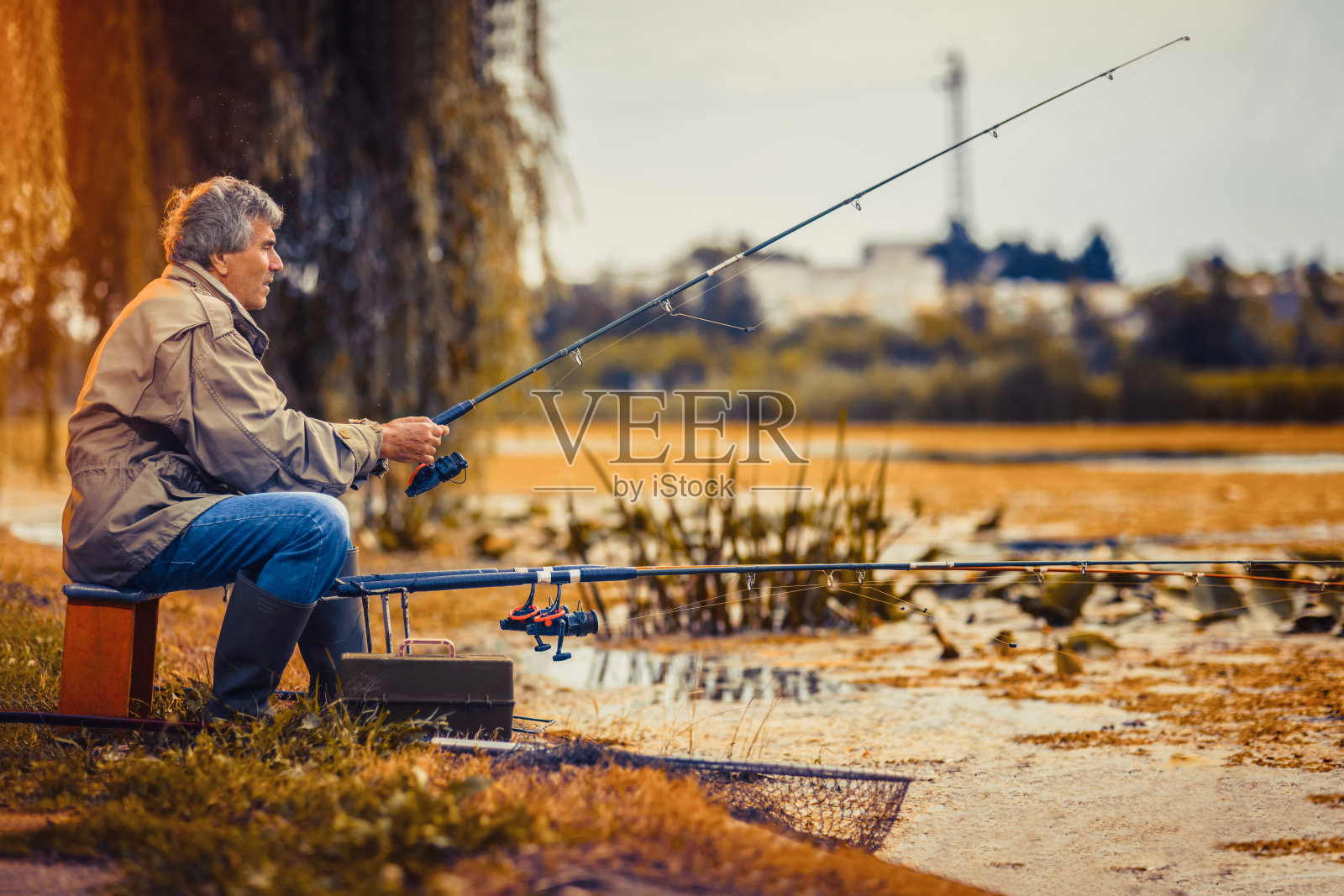老人在淡水湖上钓鱼，耐心地坐着照片摄影图片