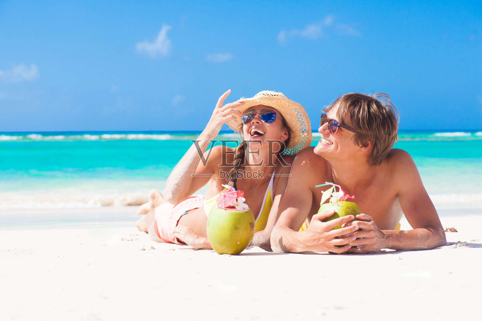 在巴巴多斯的热带海滩上，一对快乐的年轻夫妇正在吃椰子照片摄影图片