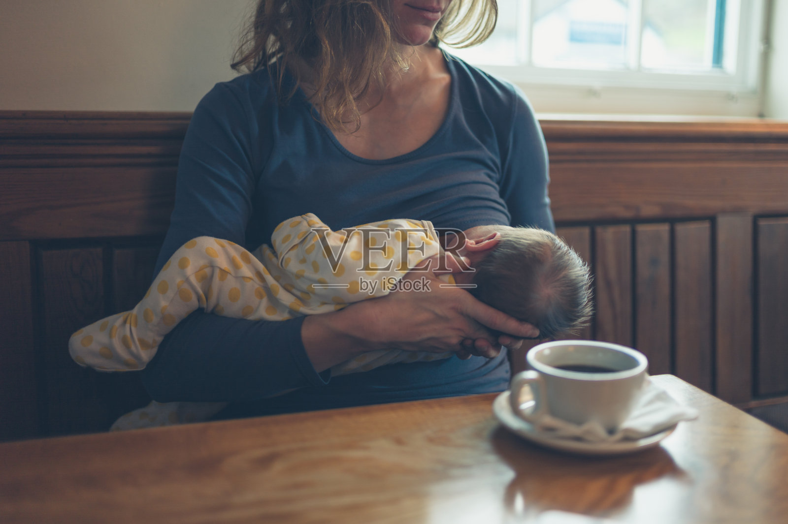 一名妇女在咖啡馆给婴儿喂奶照片摄影图片