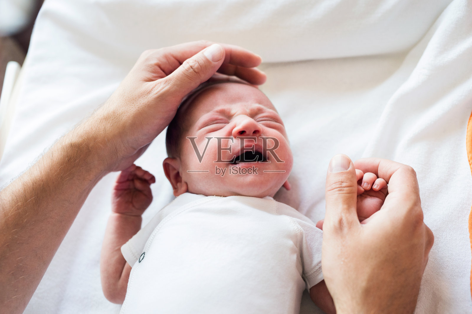 一位面目人非的父亲爱抚着啼哭的新生儿照片摄影图片
