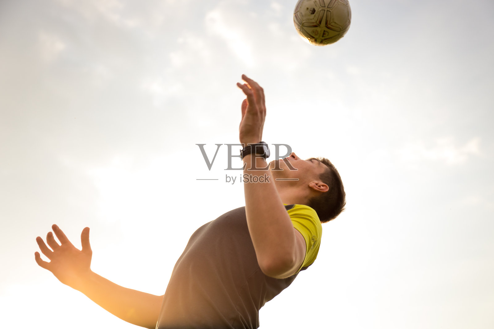 年轻的男人在沙滩上踢足球照片摄影图片
