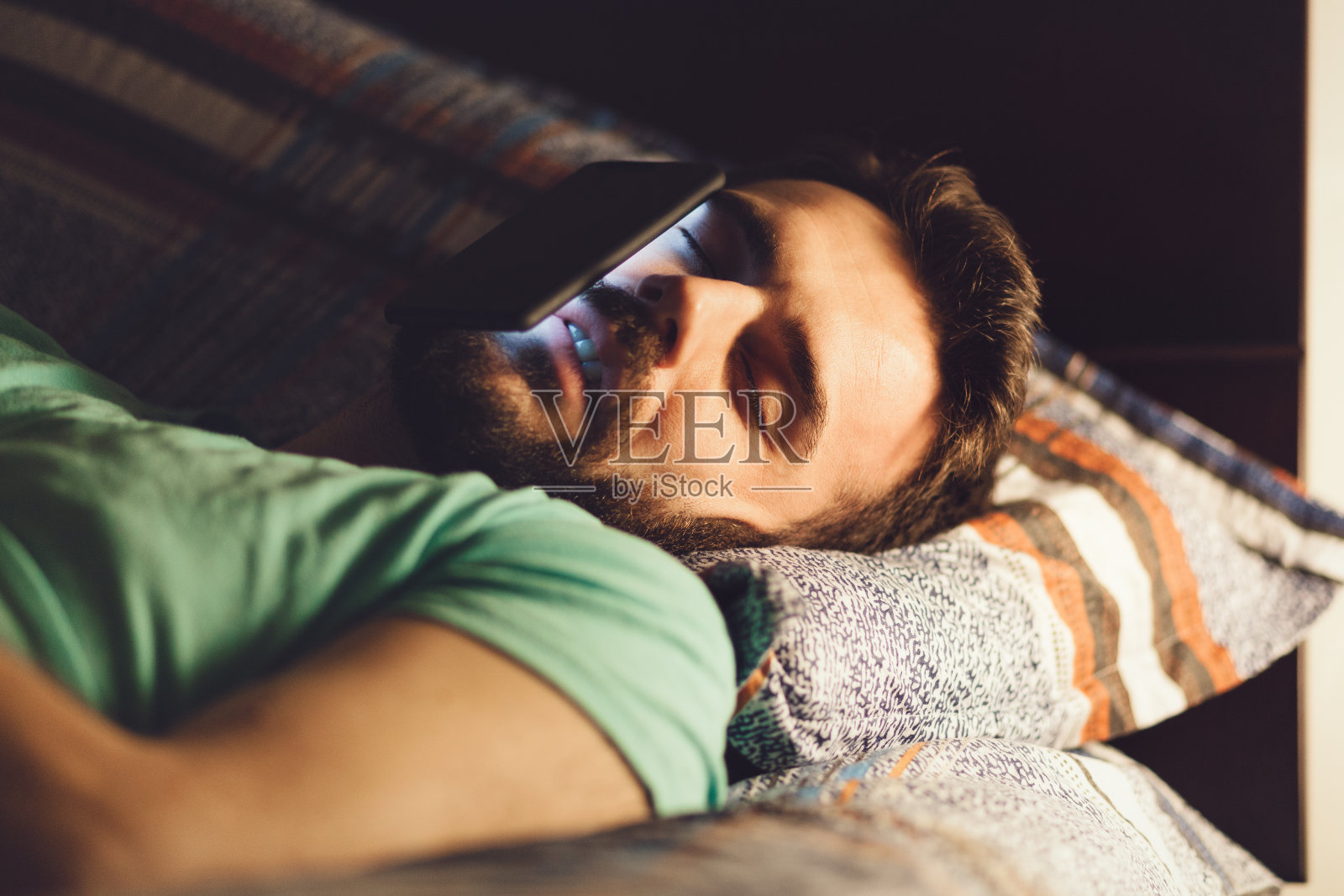 一个年轻人在床上用智能手机照片摄影图片