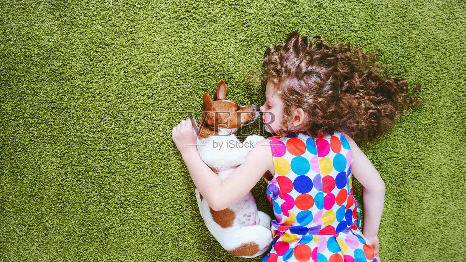孩子和小狗睡在绿色的地毯上。照片摄影图片