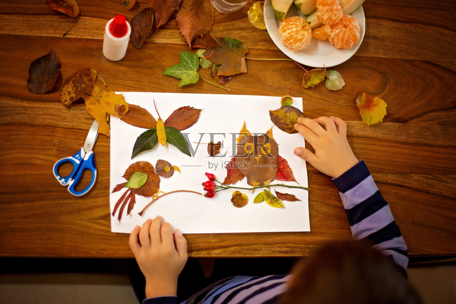 可爱的孩子，在画画的时候用胶水涂树叶照片摄影图片