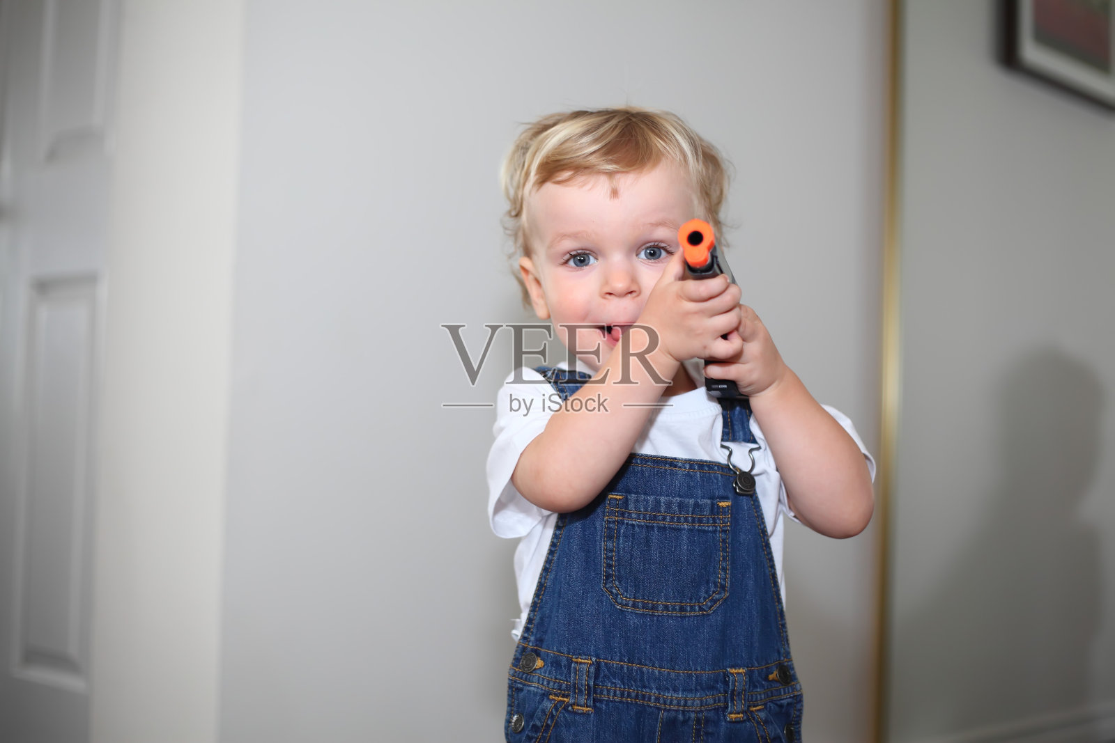 小男孩用他的玩具枪指着照片摄影图片