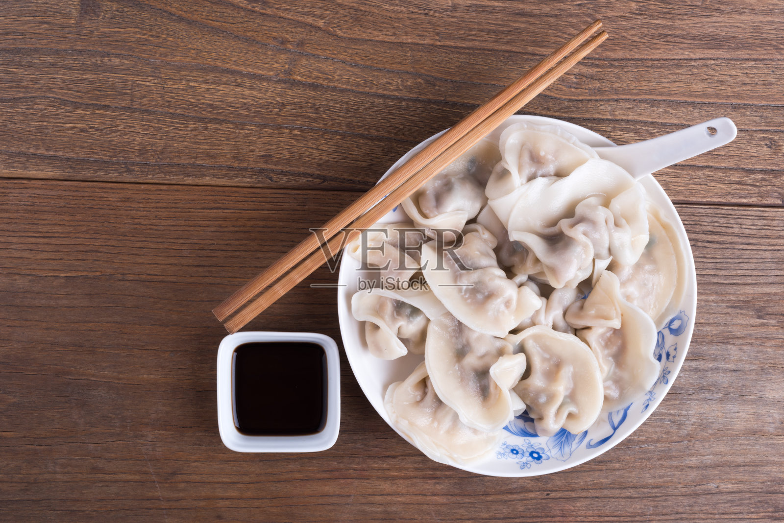 放在木桌上的装有蒸好的中国饺子的盘子照片摄影图片