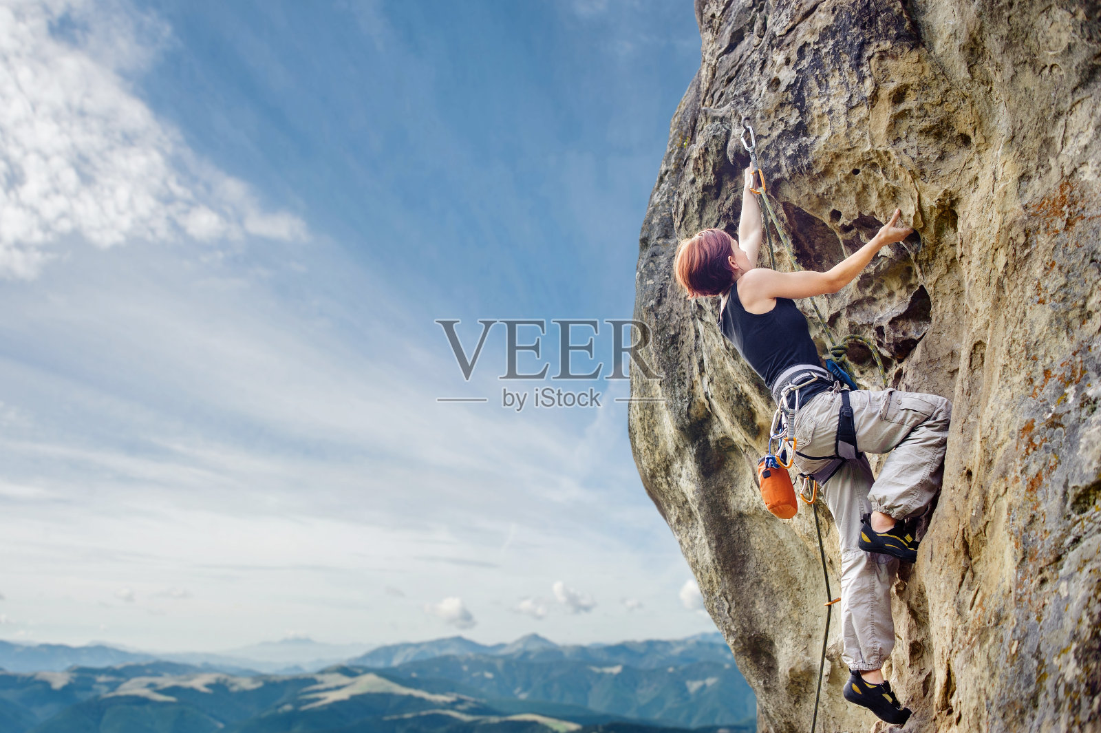 在陡峭的悬岩悬崖上的女性攀岩者照片摄影图片