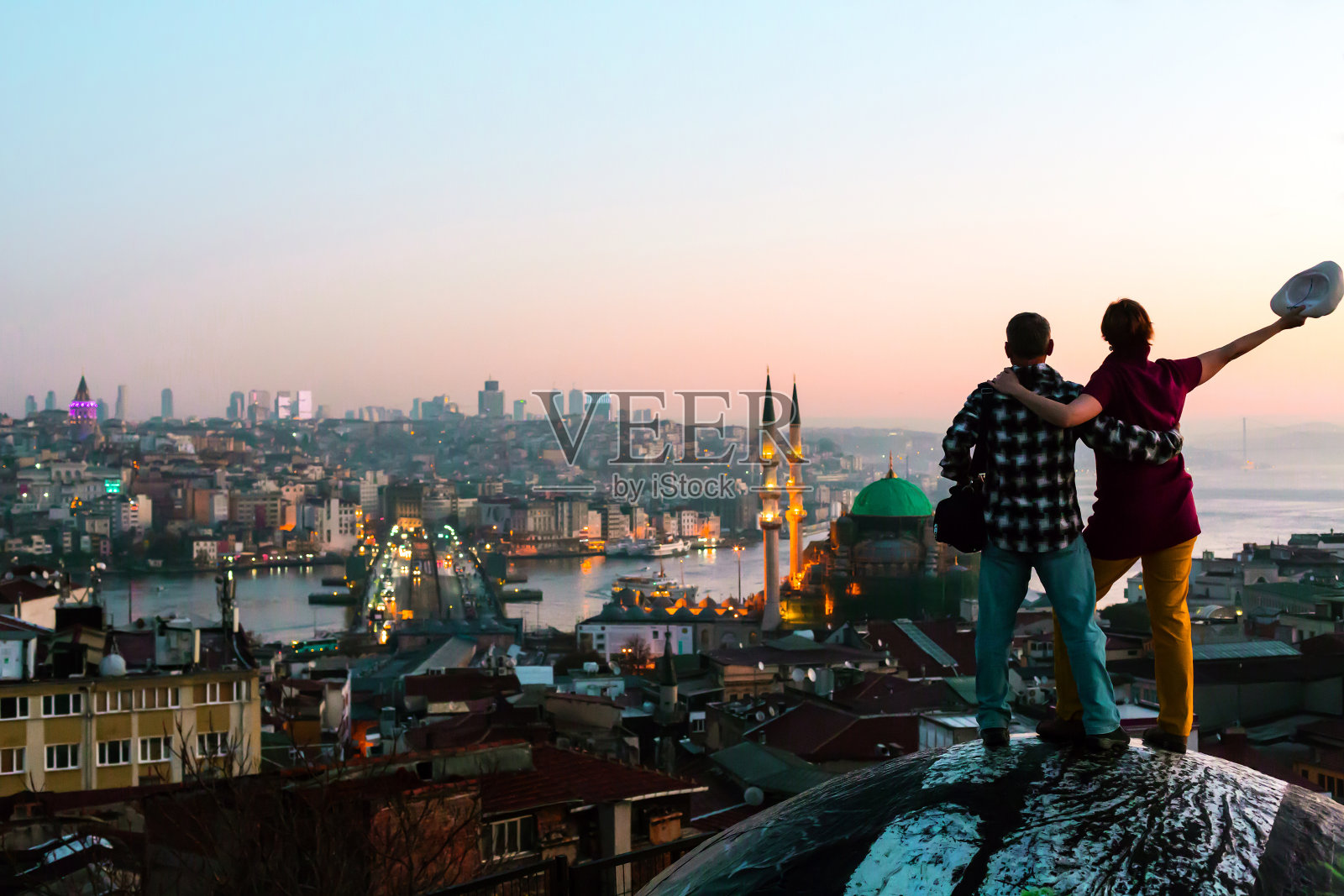兴奋的男人和女人呆在屋顶俯瞰城市在日出照片摄影图片